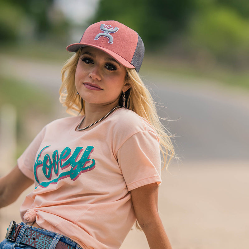 Hooey Varsity peach tee with teal logo on model