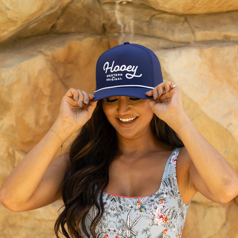 navy blue and white Hooey original hat and blue floral pattern swim suit worn by female model 