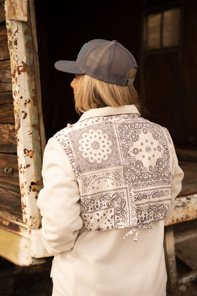 female model wearing grey cap and white and black bandana jacket