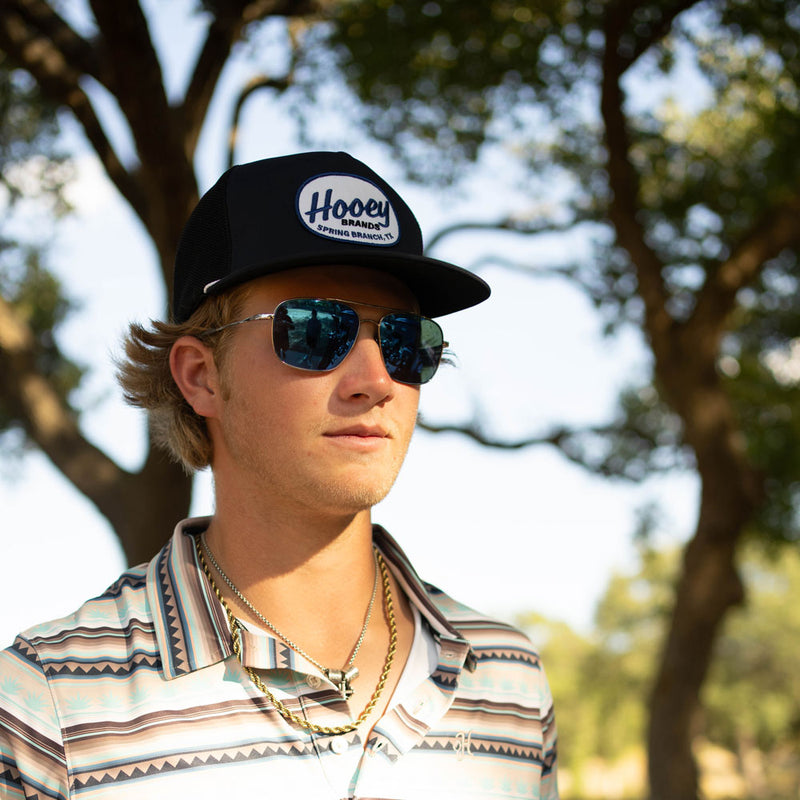 black and white hat and black, white, tan polo worn by model