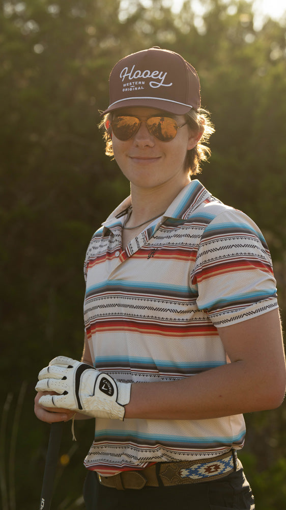 male model posing in blue, orange, red, white multi pattern golf polo