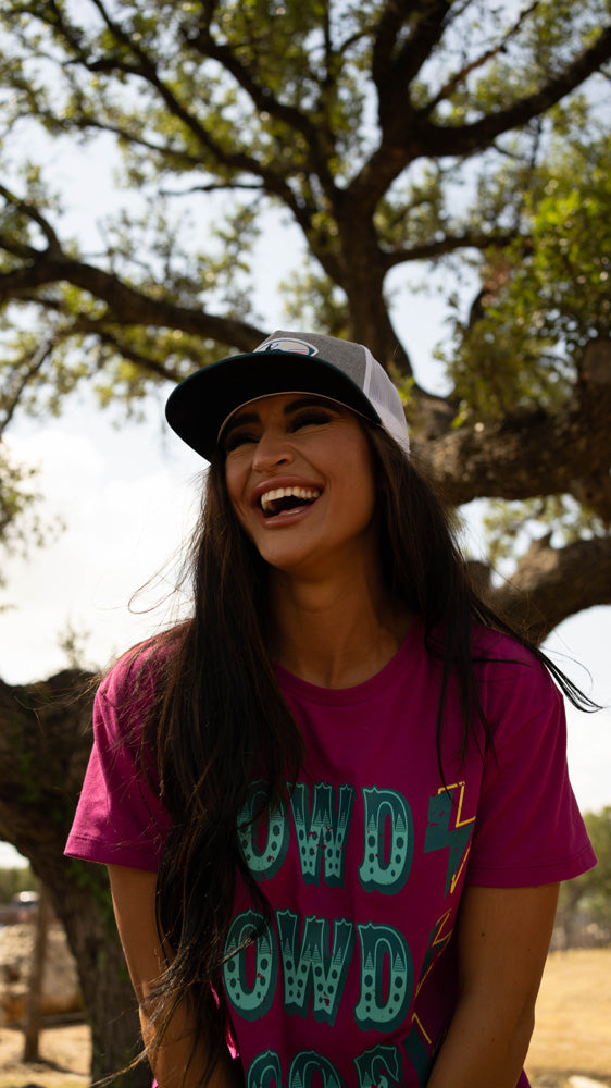 female model posing in purple Howdy Rowdy tee with hooey hat