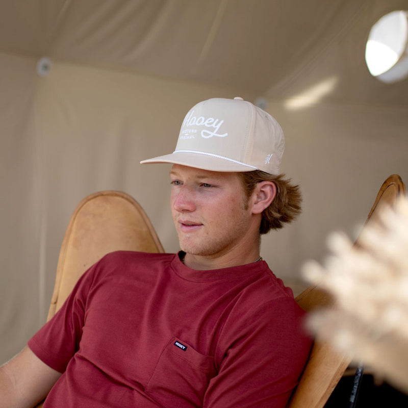 male model wearing red tee and tan hat