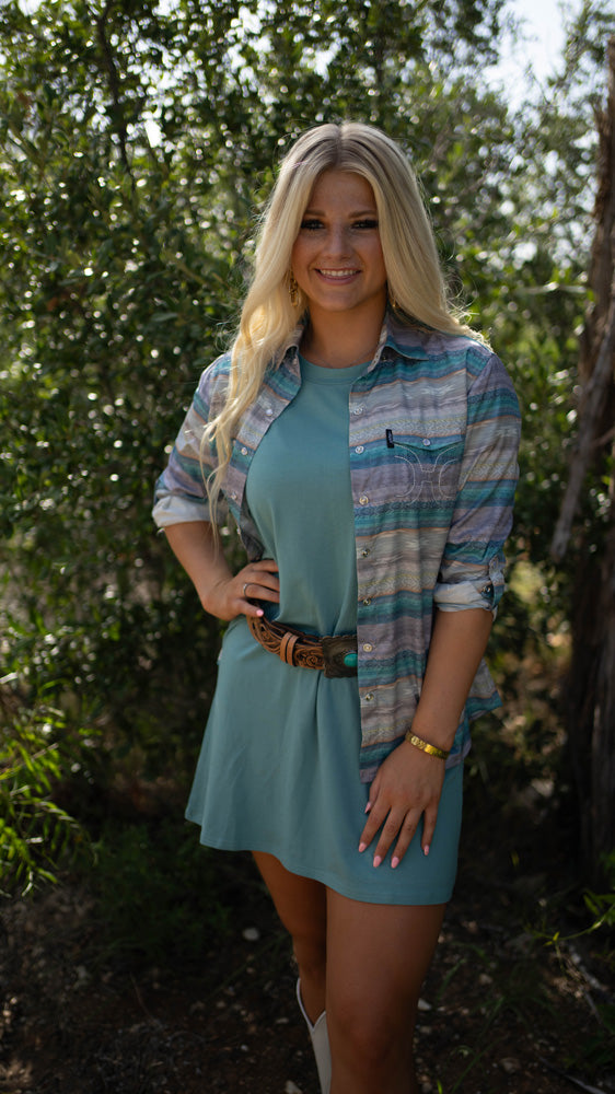 close up of female model wearing Hooey bamboo dress in blue with purple and blue serape shacket and Hooey leather belt