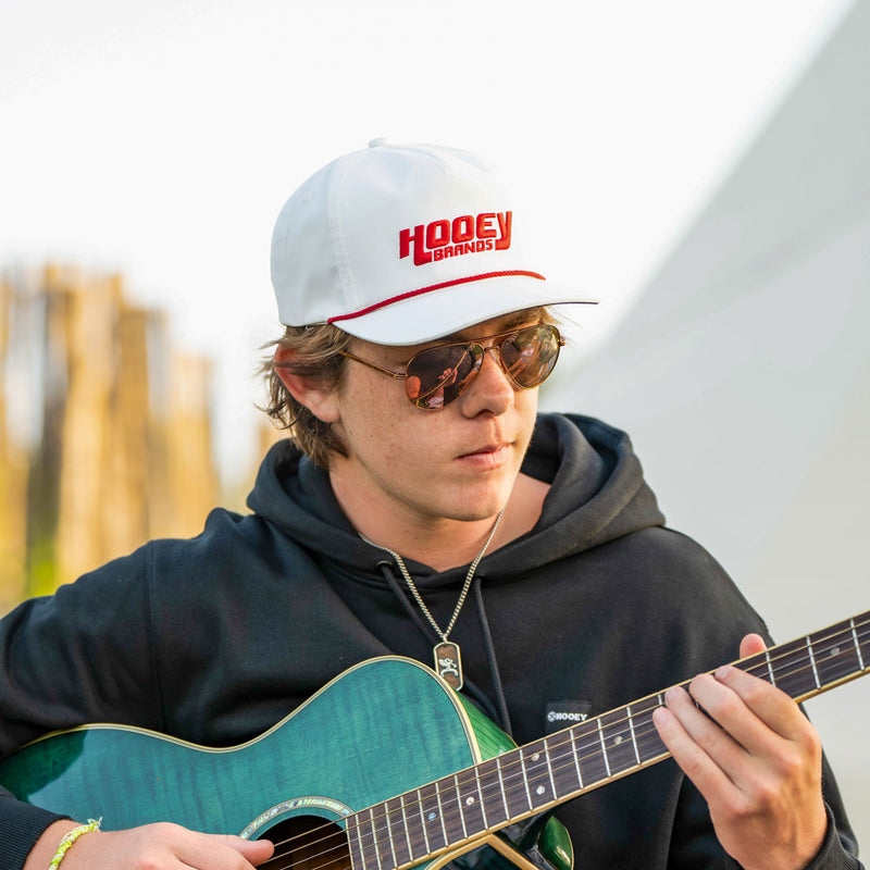 male model wearing white and red hooey hat