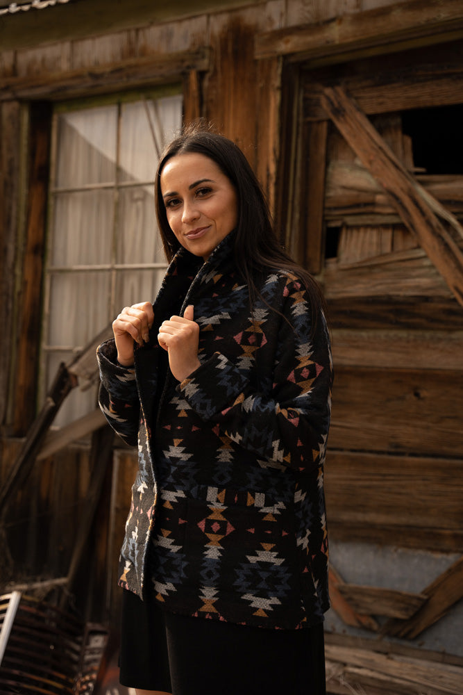 female model sporting black jacket with orange, white, blue Aztec pattern jacket