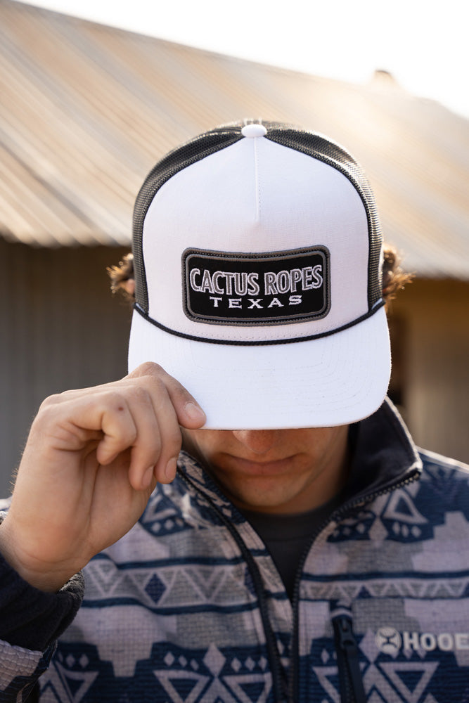 male model wearing white and black cactus ropes hat with navy and white aztec pattern pullover