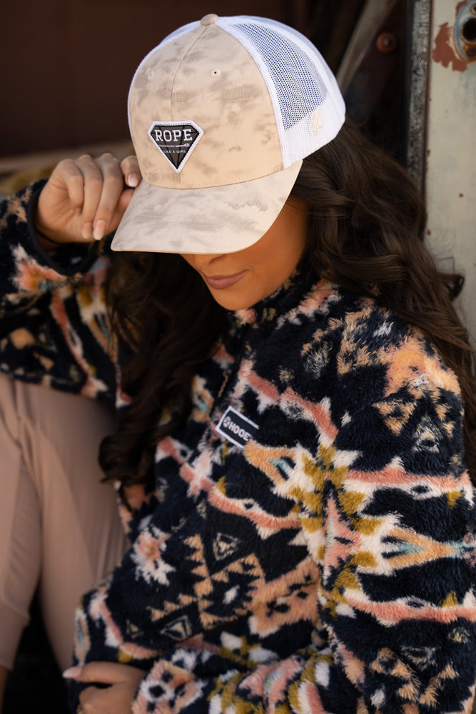 lifestyle image of a female model sporting the white and cream hat with smudge pttern