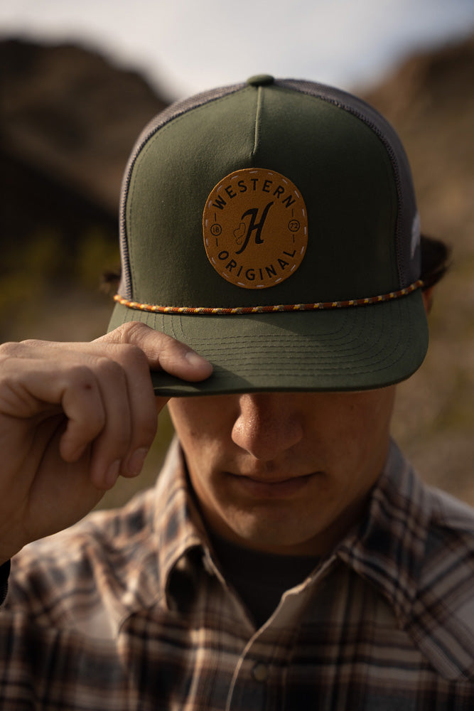 male model wearing borwn, black, white, plaid shacket with olive and grey hat