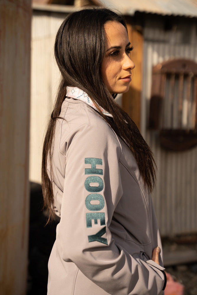 brunette female model wearing pink Hooey jacket with black logo on the sleeve