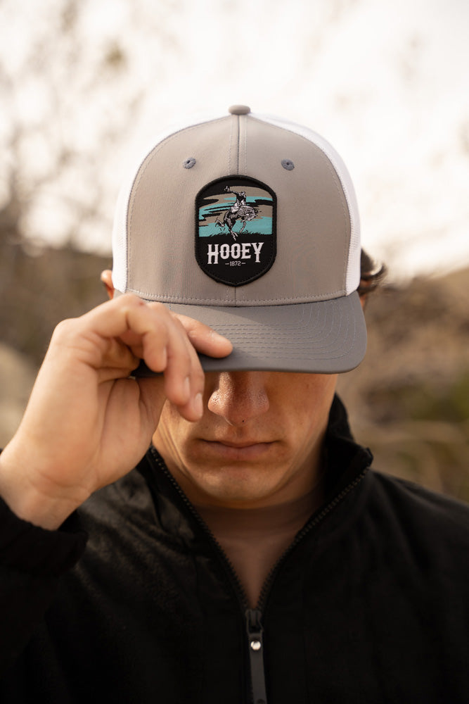 Male model wearing black jacket with gray and white Cheyenne Hooey hat pulled over eyes