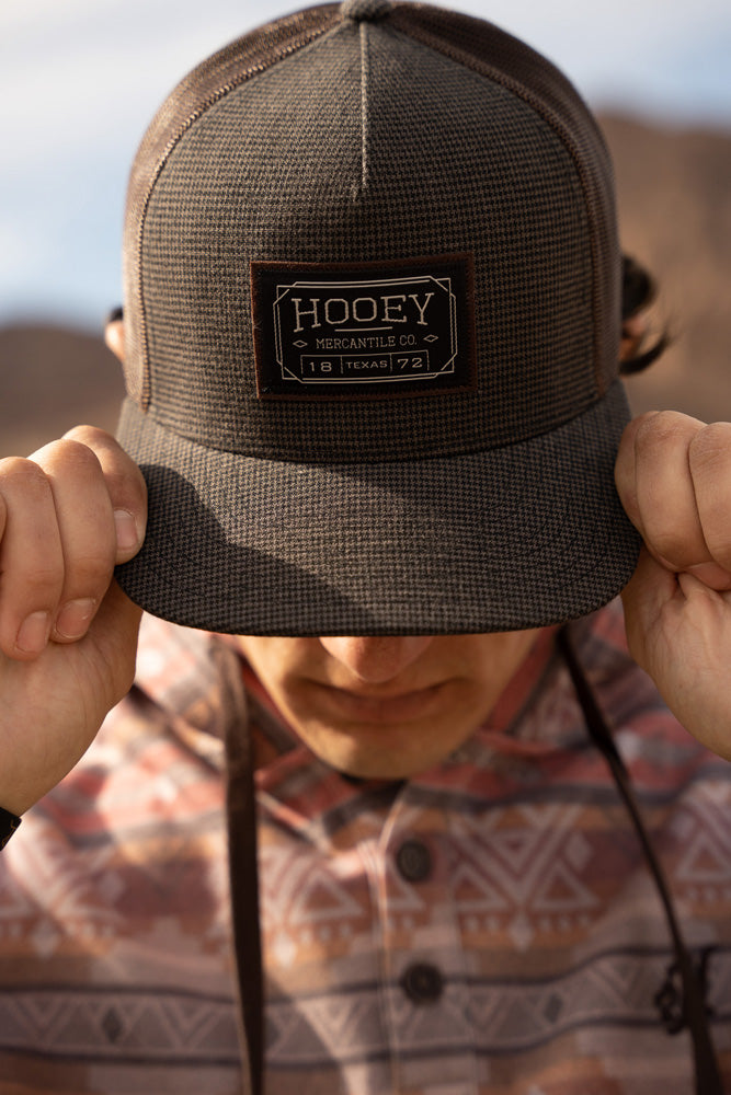 male model wearign mulit colored fleece pullover with black and charcoal hooey hat pulled over eyes with both hands