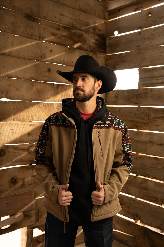 male model wearing dark blue jeans, black hoody and tan hooey jacket