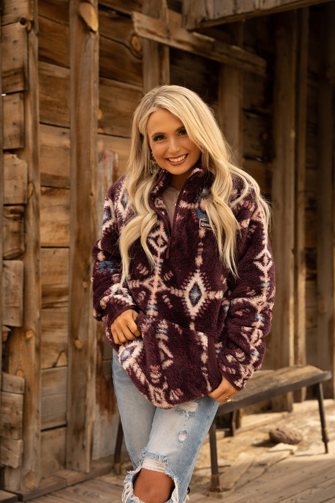 blonde female model wearing acid wash ripped jeans and maroon fleece pullover with aztec pattern