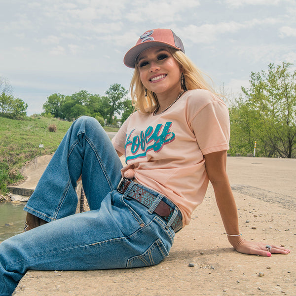 lifestyle image of the Hooey Varsity peach tee with teal logo